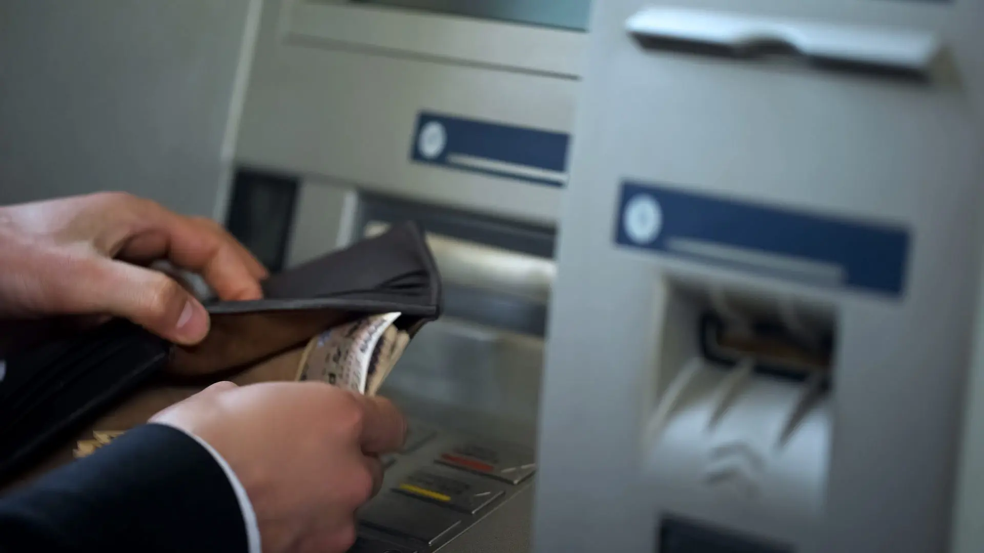 ATMで財布を出しているスーツ姿の男性