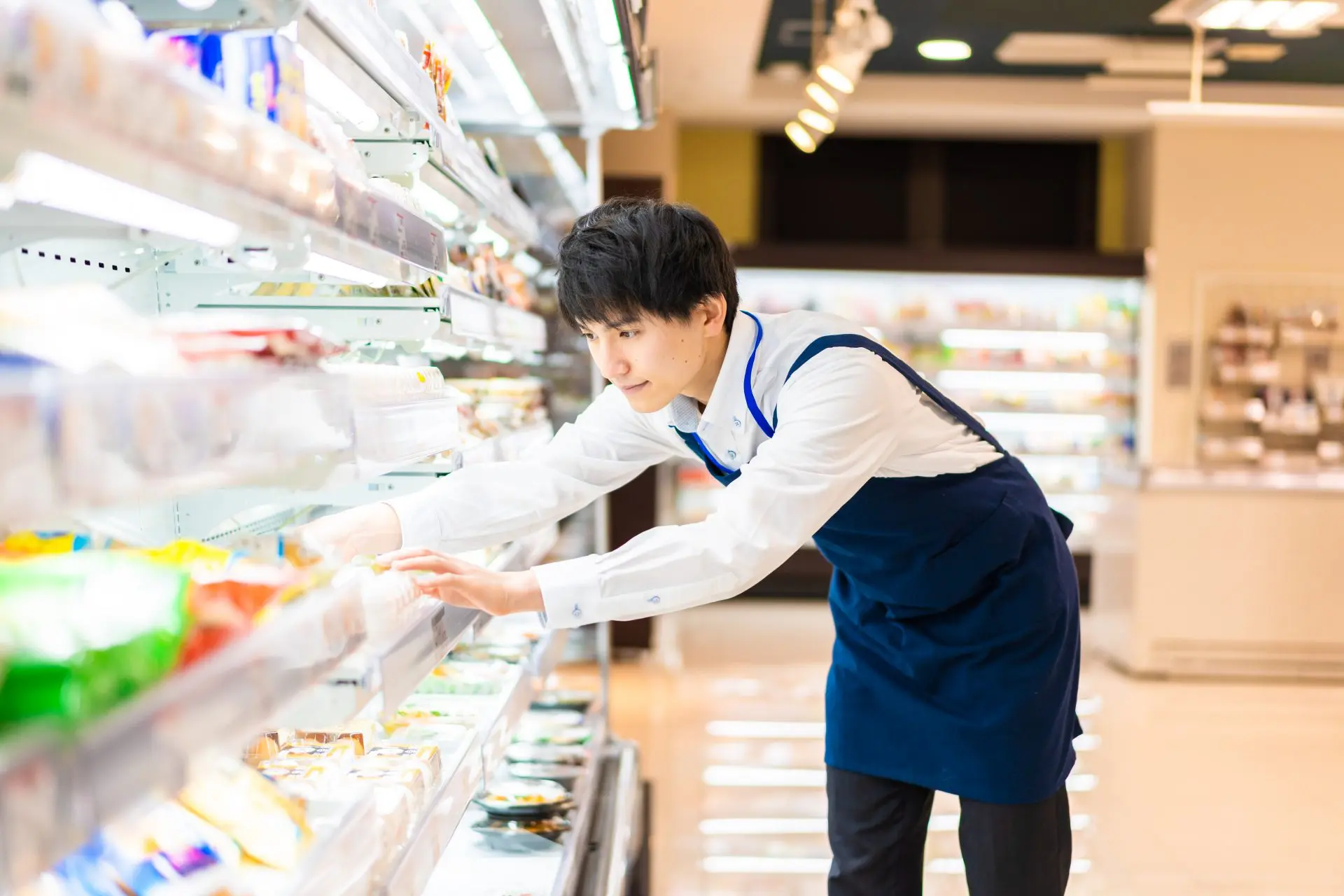 スーパーの食料品コーナーで陳列をしている若い男性